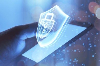 A hand holding a smartphone which displays a glowing digital shield, representing blockchain security and data protection technology. 