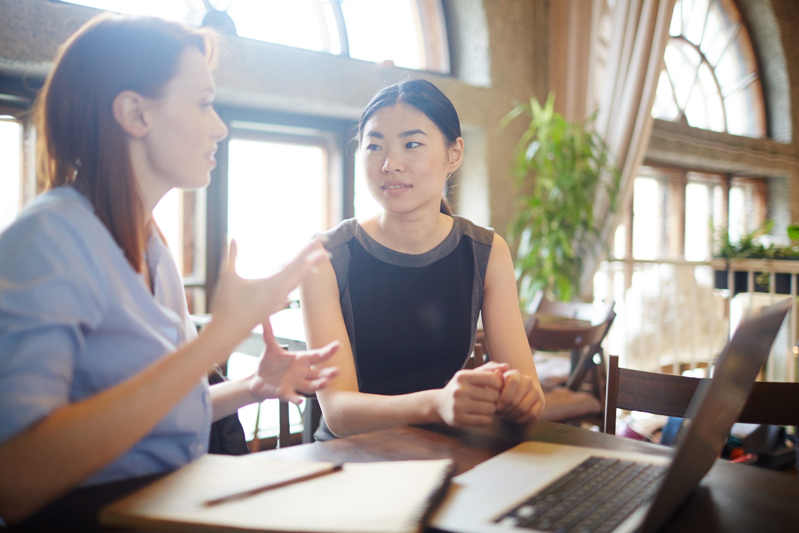 Two women engaged in a conversation at a workspace. Image by pressfotoa on Freepik.